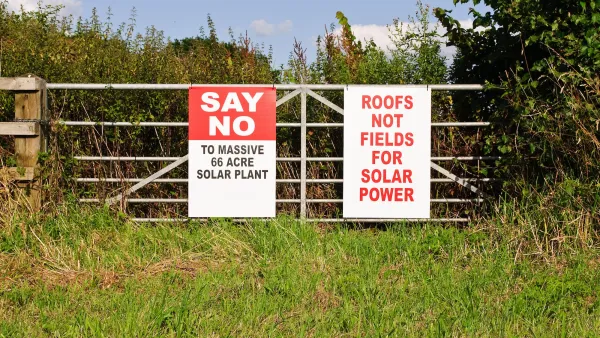 Red and white anti-solar installation signs on farm fence.