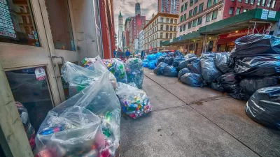 Black and blue bags of trash piled on a New York City sidewalk