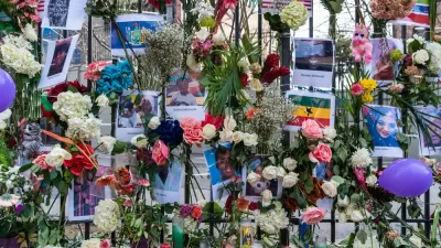 Close-up of fence covered with flowers, flyers, and other memorial items at site of deadly Twin Parks building fire