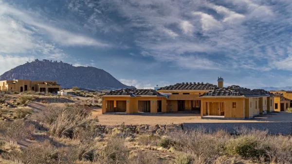 New wood-frame single-famly houses being built in Arizona with desert mountains in background.