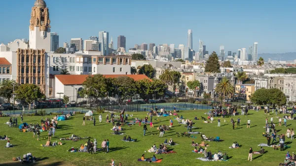 People sitting on large lawn in San Francisco city park.