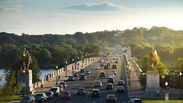 Traffic on the Arlington Memorial Bridge in Washington, DC with neoclassical buildings in background at golden hour.