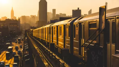 Golden sunset view of New York City subway train on elevated track with Empire State Building in background