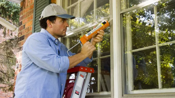 Worker caulking cracks in a home window