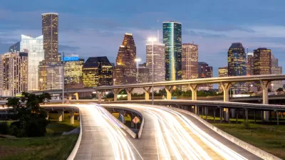 Dusk view of blurred car lights passing on freeway with Houston skyline in background