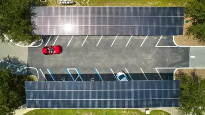Overhead view of parking lot with solar panel canopies over parking spots and red car driving in