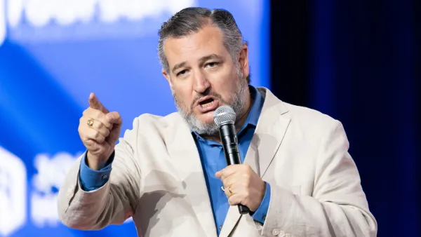 Senator Ted Cruz holding microphone speaking at an event on stage.
