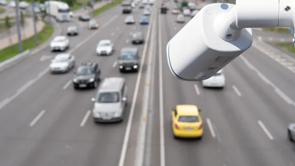 Close-up on white traffic camera installed over a busy roadway.