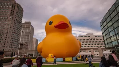 Giant inflatable yellow rubber ducky placed in plaza at Huntington Place, Detroit with pedestrians milling around