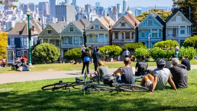People lounging on grass in Alamo Square park in San Francisco overlooking painted ladies Victorian houses and city skyline