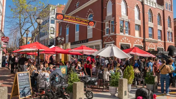 Busy street scene in Salem, Massachusetts with old brick church in background and red and white patio umbrellas.