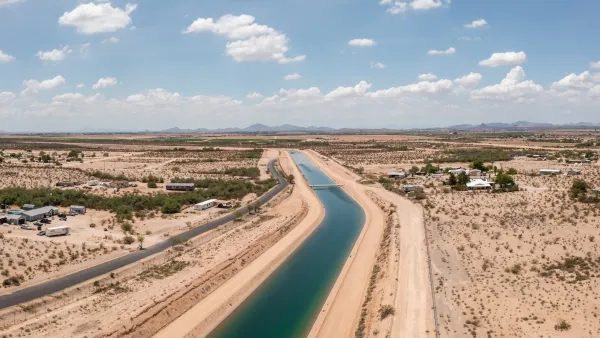 Aerial of Central Arizona Project aqueduct full of dark turquoise water surrounded by Arizona desert.
