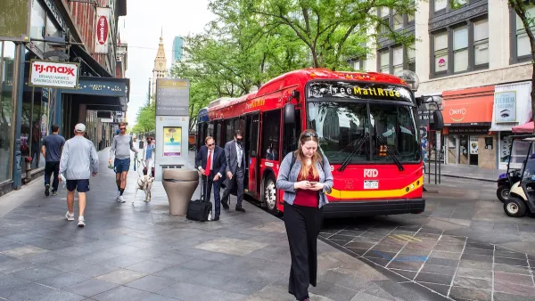People walking in Denver next to a red bus.