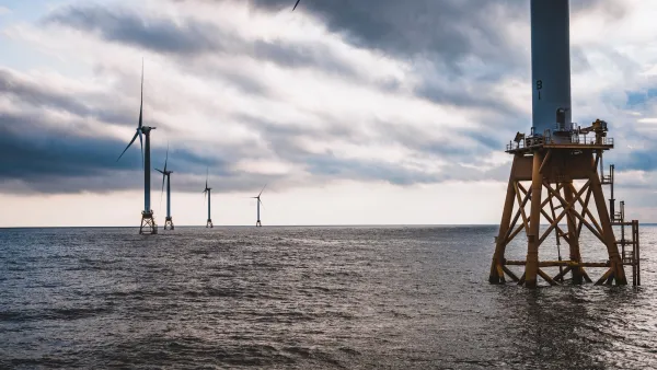 Offshore wind turbines on calm water with yellow scaffolding base.
