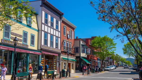 A lively town street with shops and people walking by colorful buildings