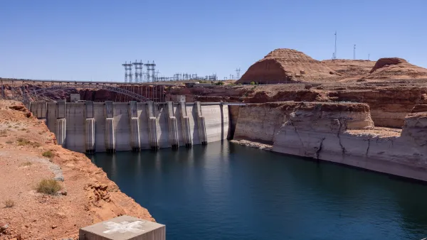 Lake Powell and dam surrounded by red rocks with visible 'bathtub rings' during drought.