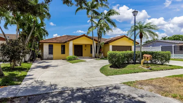 Yellow one-story house on residential street in Miami, Florida.