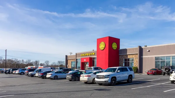 Red and yellow Gold's Gym building with parking lot in front in Harrisburg, North Carolina.
