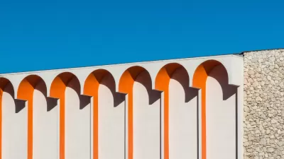 Close-up of white building with orange arch details against blue sky in Palm Springs, California