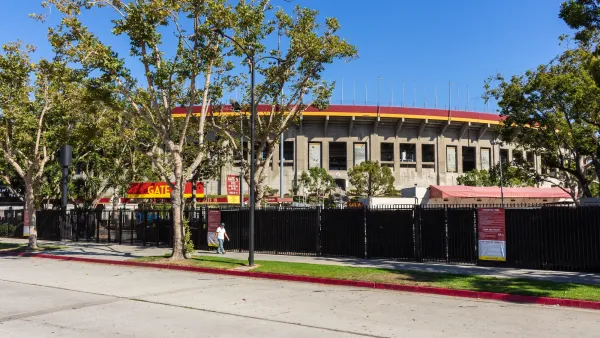 Man walkingon sidewalk in front of Los Angeles Memorial Coliseum sports stadium.