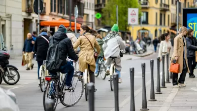 People on bikes and pedestrians walking on busy city street in Milan, Italy