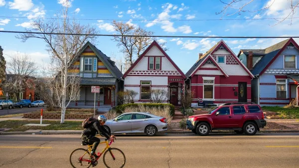 Cyclist rides past row of colorful historic homes in Denver, Colorado.