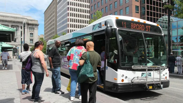 White RIPTA transit bus in Providence, Rhode Island with crowd of passengers boarding at bus stop.