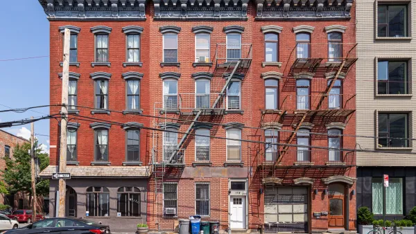 Red NYC brick apartment buildings with closed, unlabeled comemrcial space on ground floor.