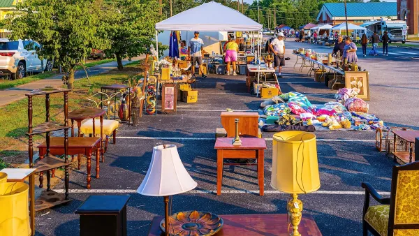 Tables full of second hand stuff set up in parking area with canopies over them and vintage lamps on tables in foreground.