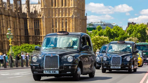 Line of traditional London black cabs passing in front of Westminster Abbey.