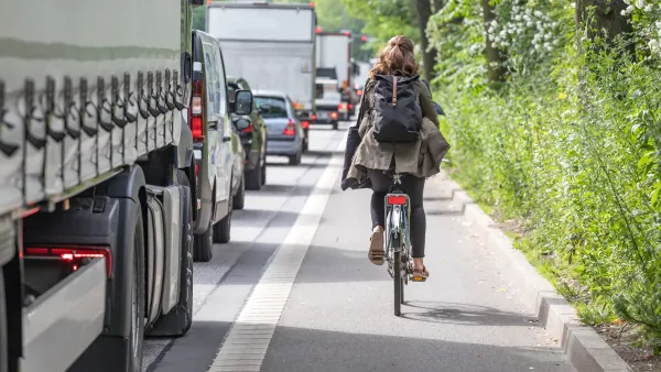 A woman biking on a narrow bike lane next to a truck.