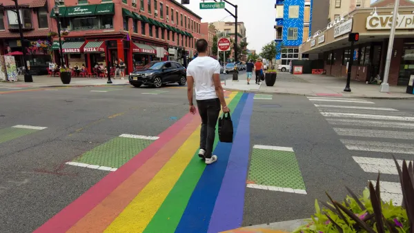 Man crossing rainbow-painted crosswalk in Hoboken, New Jersey.