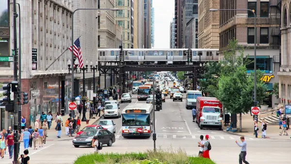 People in Chicago cross the street. There are two CTA buses in the background.