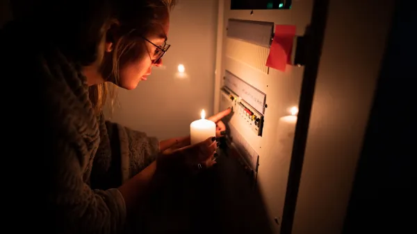 Person holding up candle to power panel in the dark.