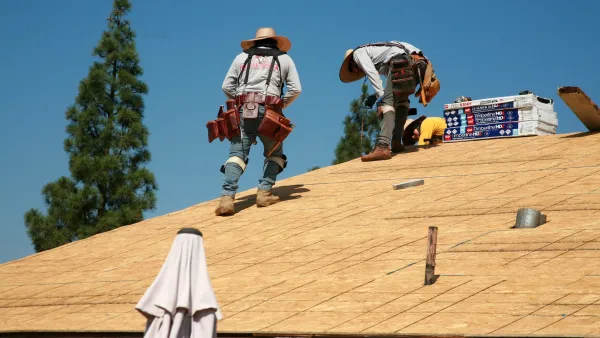 Workers on a wood roof building a home.