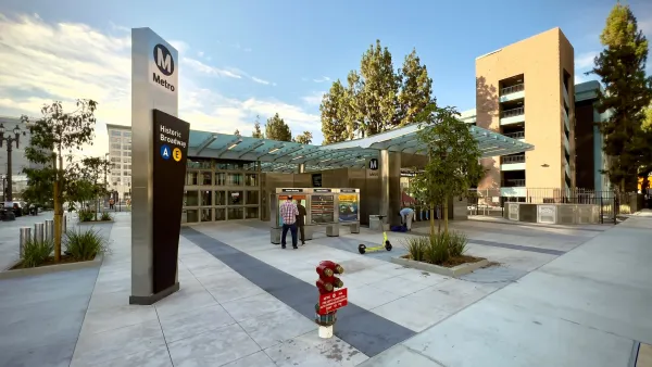 Sign at entrance to underground LA Metro station with parking building in background.