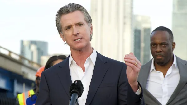 Gavin Newsom speaks behind a podium and gestures with one hand.