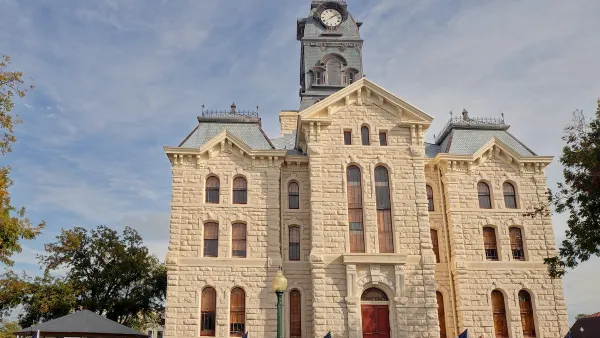 Old Hood County courthouse made of white stones with clock tower in Texas.