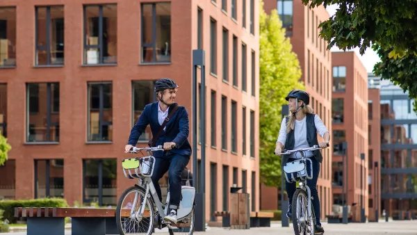 Young man and woman on bike share bikes riding in city.