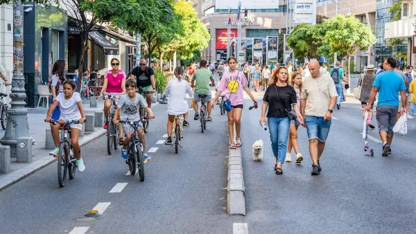 Busy street closed to vehicles in center of Bucharest, Romania full of pedestrians and people on bikes and scooters.