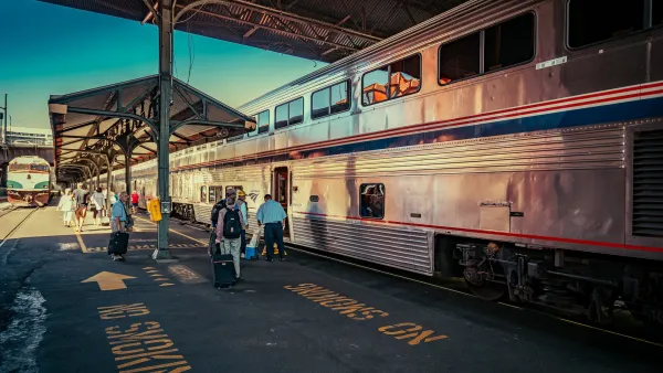 People on train platform next to silver Amtrak train in Portland, Oregon.