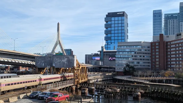 A gray and purple MBTA commuter rail train crossing the Charles River on the North Station Draw One Bridge.