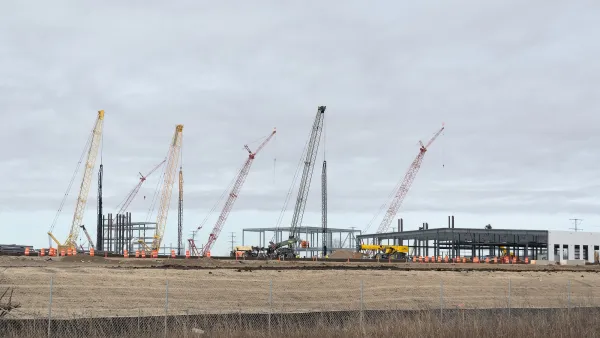 Large building for Microsoft data center under construction with cranes and heavy equipment in flat treeless field in Mt. Pleasant, Wisconsin.