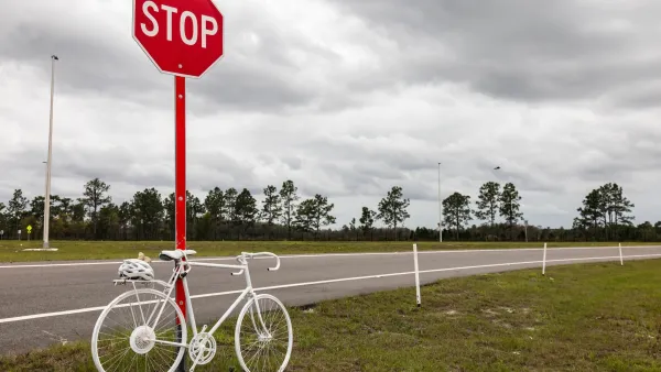White memorial ghost bike tied to a stop sign on rural road.