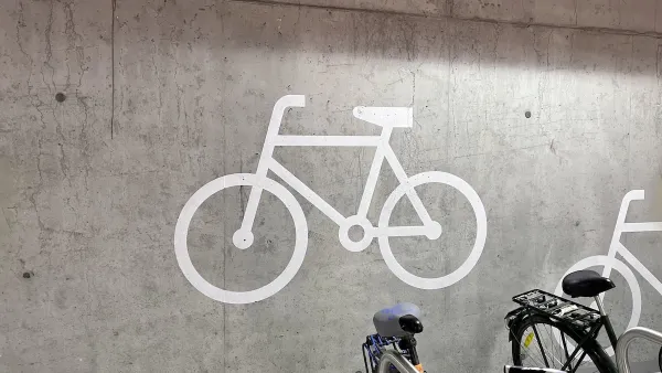 Bike parking logo on concrete wall in garage with parked bike visible in bottom corner.