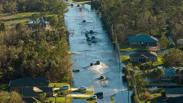 urricane flooded street with moving cars and surrounded with water houses in Florida residential area.