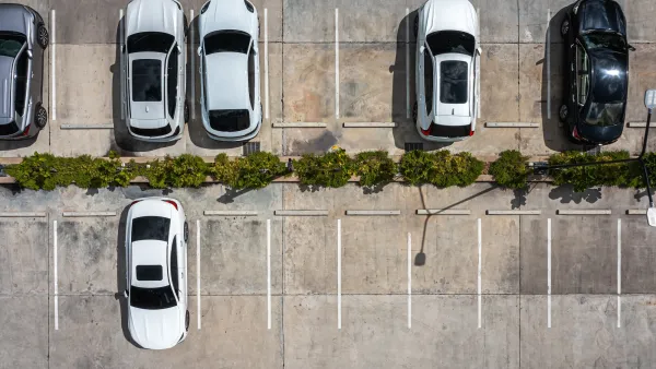 Bird's eye view of white cars in parking lot.