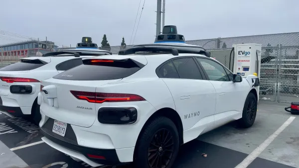 White Waymo SUV cars parked at charging station.