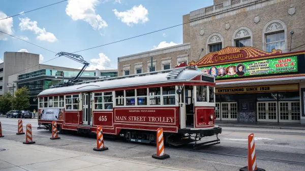 Red vintage-style Memphis trolley on street in front of old-style theater marquee.