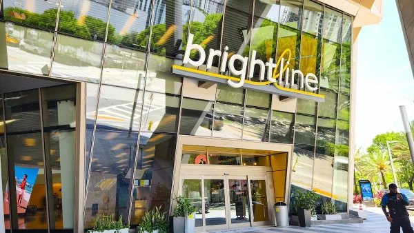 The outside of a brightline transit hub with many windows on a sunny day.